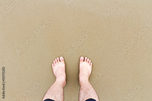 Top down view of feet on the beach with copy space