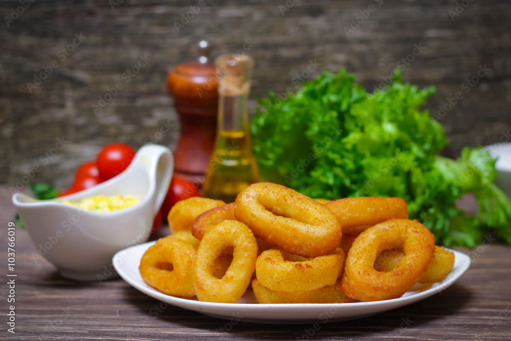 deep fried calamari with sauce and salad on a wooden background deep fried calamari with sauce and salad on a wooden background