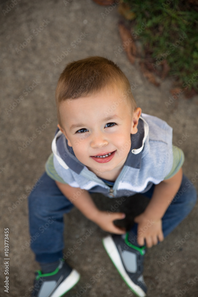 Top view of little boy standing on street looking up at camera. Top view of little boy standing on street looking up at camera.