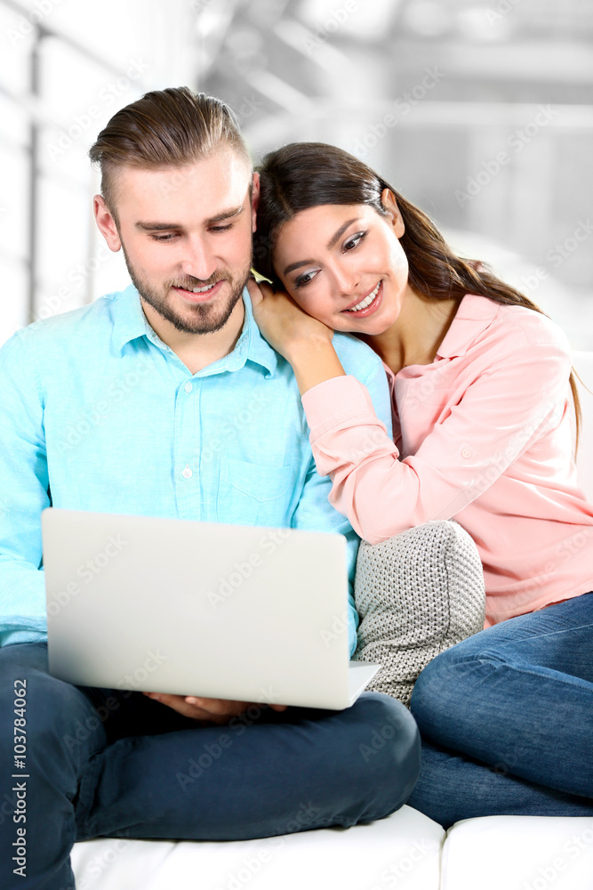 Happy couple sitting on sofa and working on a laptop Happy couple sitting on sofa and working on a laptop