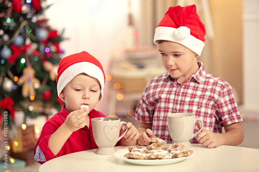 Two cute small brothers eating cookies on Christmas decoration background Two cute small brothers eating cookies on Christmas decoration background