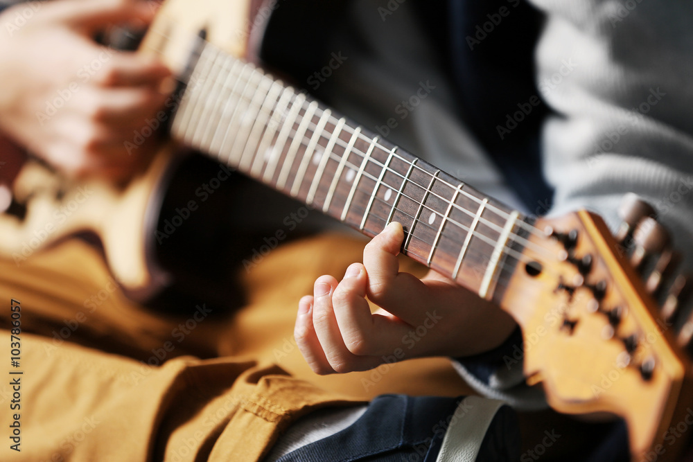 Fototapeta premium Cute little boy playing guitar on brick wall background
