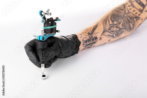 Tattooist hand in black glove with tattoo machine isolated on white background, close up