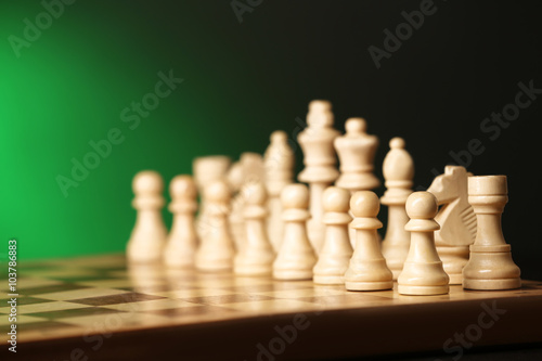 Chess pieces and game board on green background