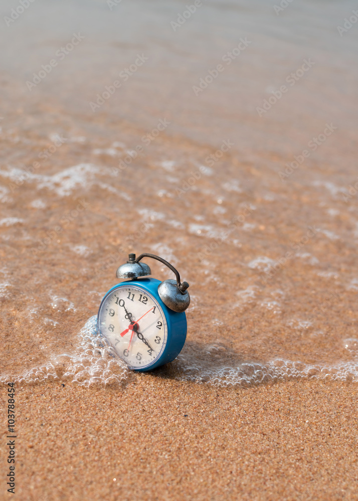 Obraz premium alarm clock on sand beach