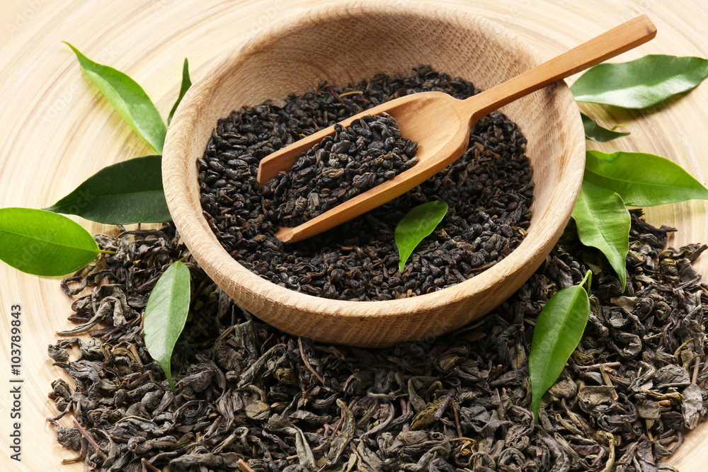 Dry tea with green leaves in wooden utensil, close up Dry tea with green leaves in wooden utensil, close up