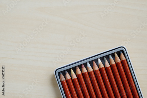 Color pencils in box on wood background