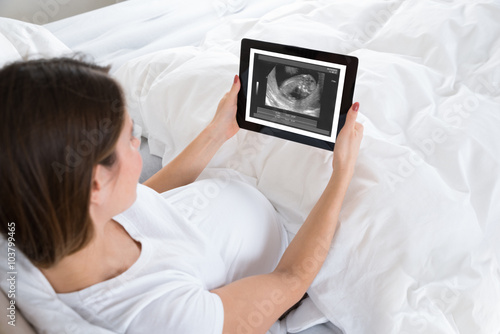Pregnant Woman Looking At X-ray On Digital Tablet