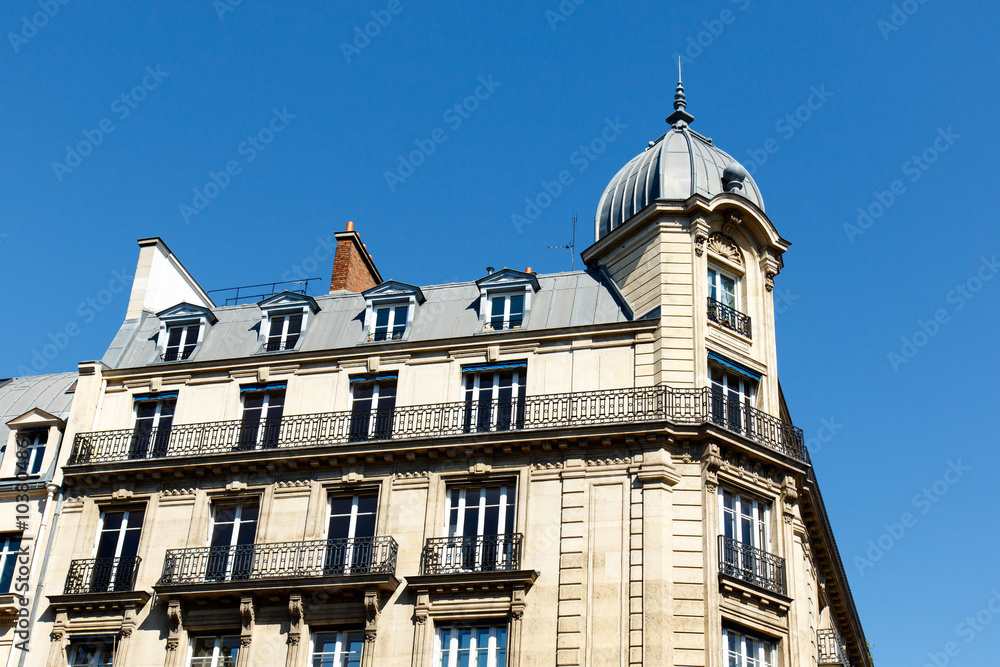 Color DSLR stock picture of an apartment building in the St. Germain neighborhood of Paris, France, with balconies a turret, and a blue sky background. The horizontal image has copy space for text