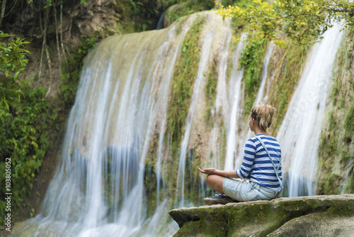 Attractive youn woman during meditation near the waterfall