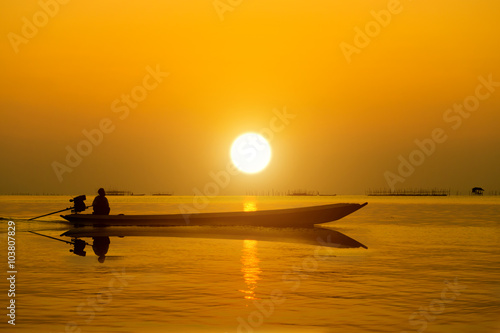 Silhouettes fisherman and sunset on the lake.