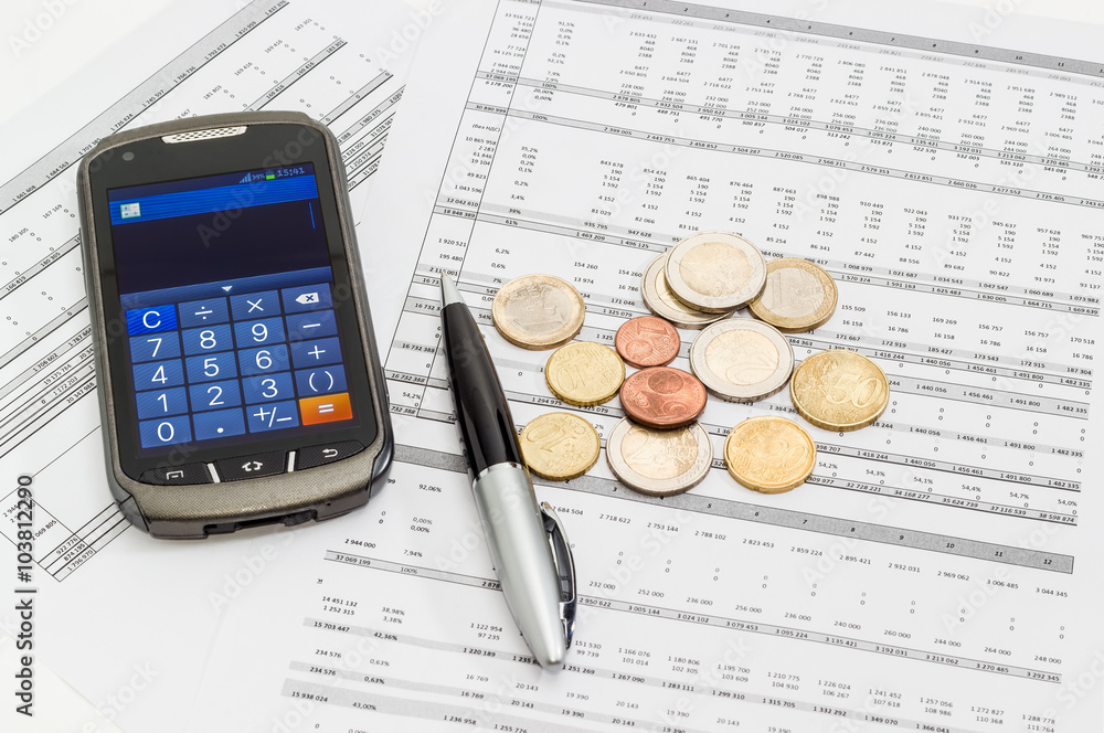 Coins, pen, smartphone in calculator mode on the data table Coins, pen, smartphone in calculator mode on the data table