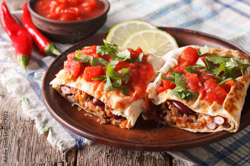 Mexican chimichanga with meat, vegetables and cheese close-up 