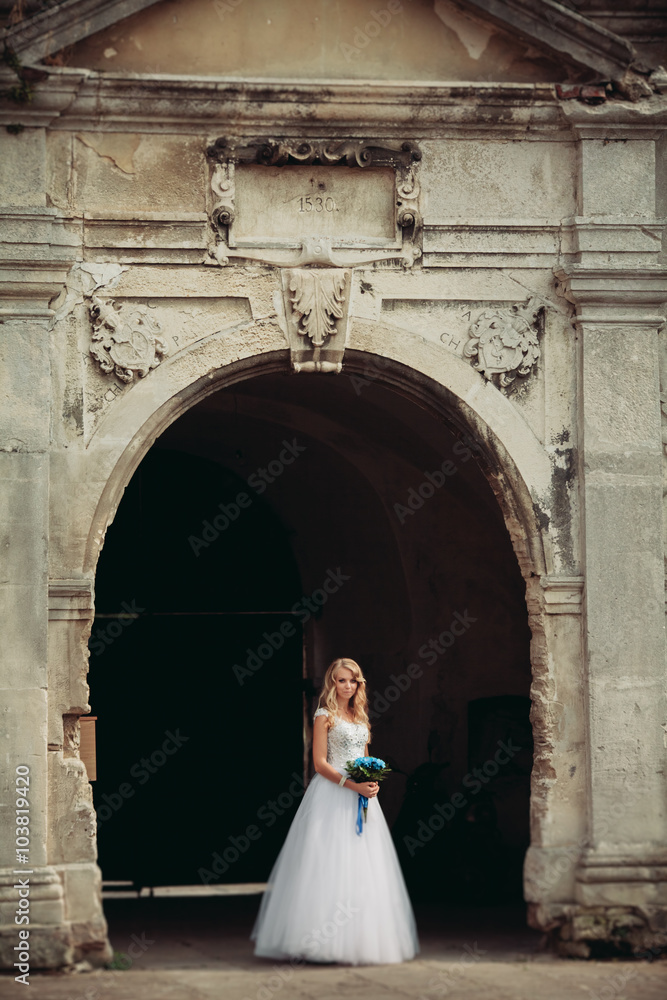 Beautiful young blond bride with bridal bouquet sitting on the stairs under gorgeous plants Beautiful young blond bride with bridal bouquet sitting on the stairs under gorgeous plants