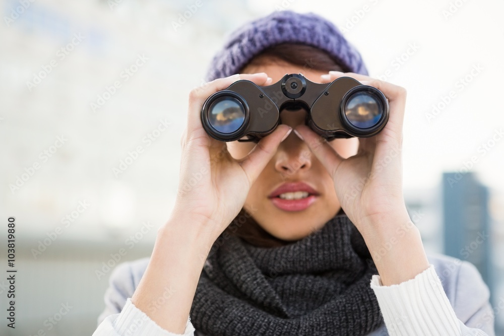 Woman with winter clothes looking into binoculars Woman with winter clothes looking into binoculars