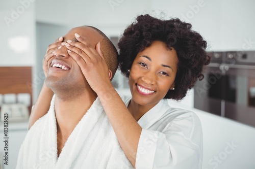 Smiling woman hiding the eyes of her husband