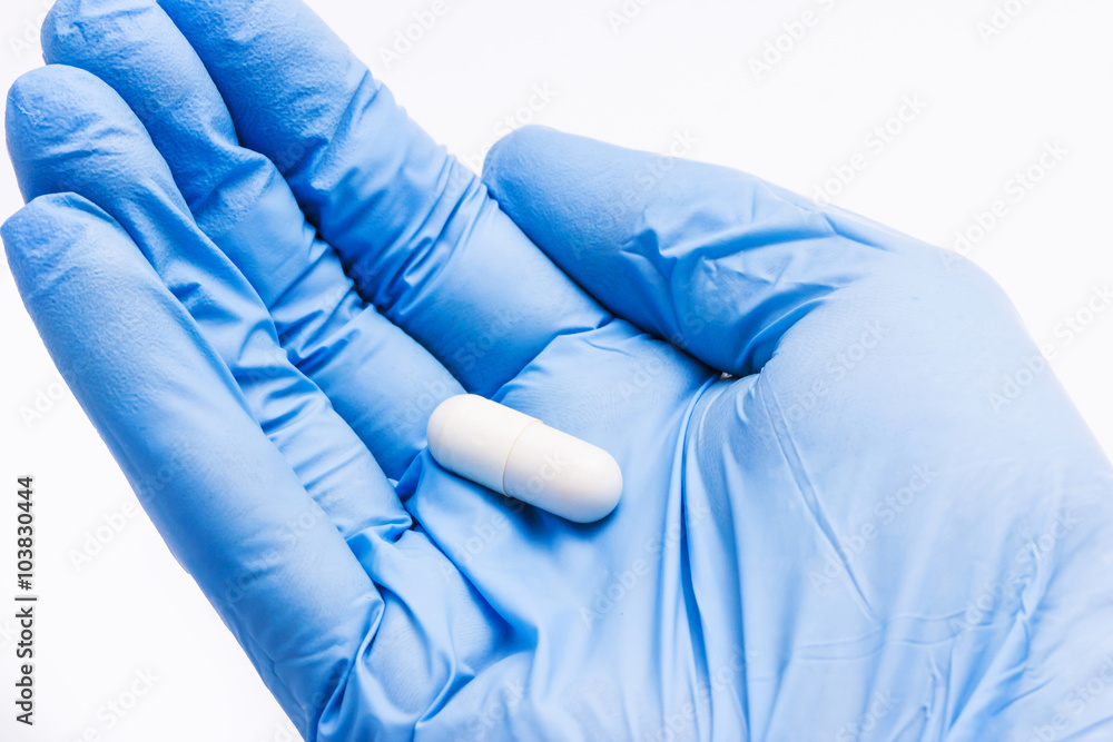 Hand in blue glove holding pills. Hand in blue glove holding pills.