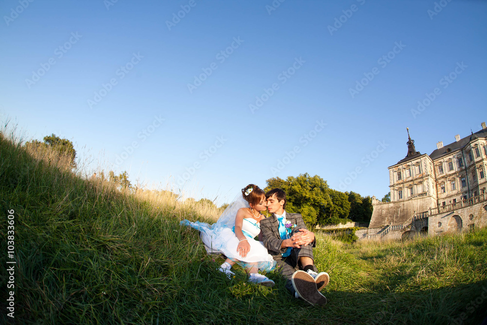 happy couple is sitting on the grass on background old castle happy couple is sitting on the grass on background old castle