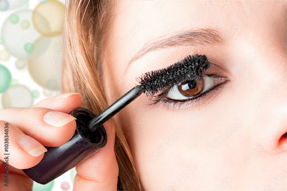 girl applies mascara to eyelashes
