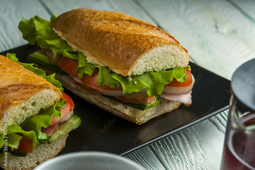 Tasty sandwiches with ham, vegetables and lettuce on black plate. Fast food. Focus on sandwich. Tasty sandwiches with ham, vegetables and lettuce on black plate. Fast food. Focus on sandwich.