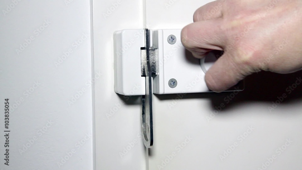 Mann schließt einen Sperrriegel an der Haustür - Man closed a locking bolt on a door at home