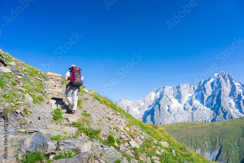 Backpacker hiking on the Alps, majestic Mont Blanc in background