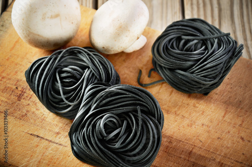 three servings of pasta with black cuttlefish ink and two mushro