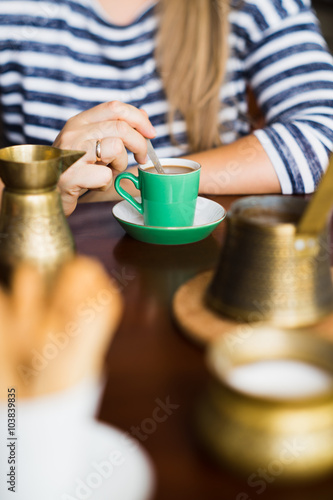 Woman stirring coffee with teaspoon. Selective focus