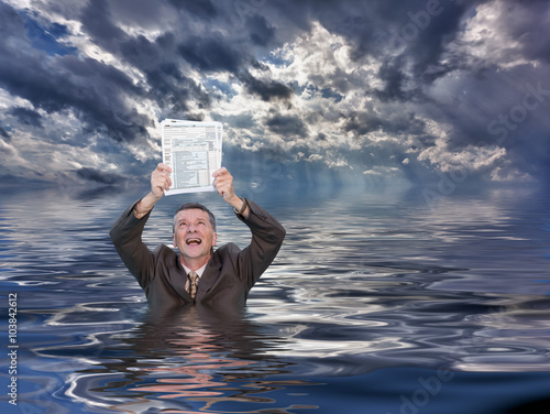 Senior man holding IRS form 1040 in water photo