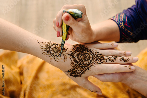 applying henna tattoo on women hands