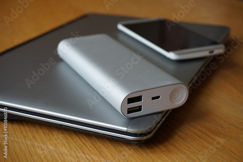 Mobile office with aluminum laptop, cell phone and power source (power bank) on the wooden table 