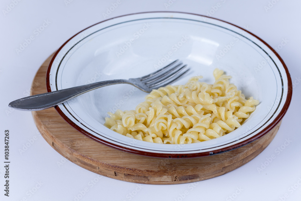 Cooked macaroni served in the plate over white Cooked macaroni served in the plate over white
