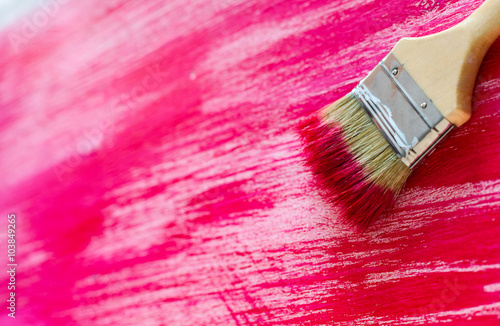 Brush painting wooden furniture with red, close-up