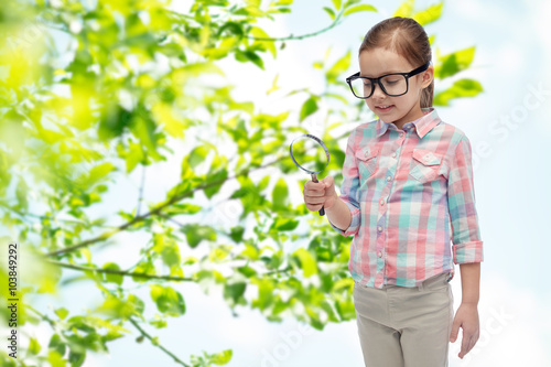 little girl in eyeglasses with magnifying glass