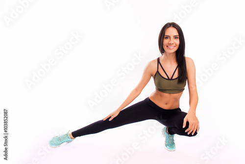 Young fit smiling sportswoman stretching on white background
