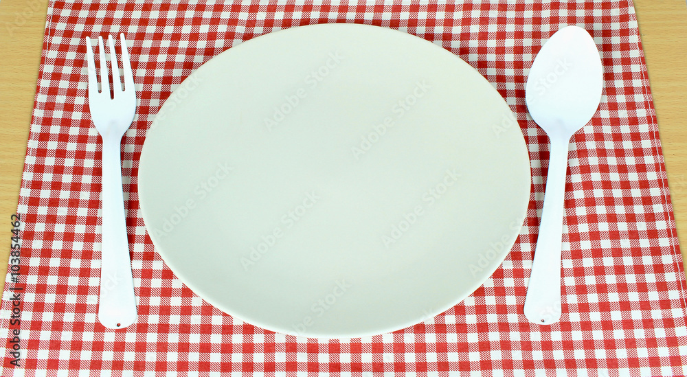 plate between spoon, fork on red tablecloth texture plate between spoon, fork on red tablecloth texture