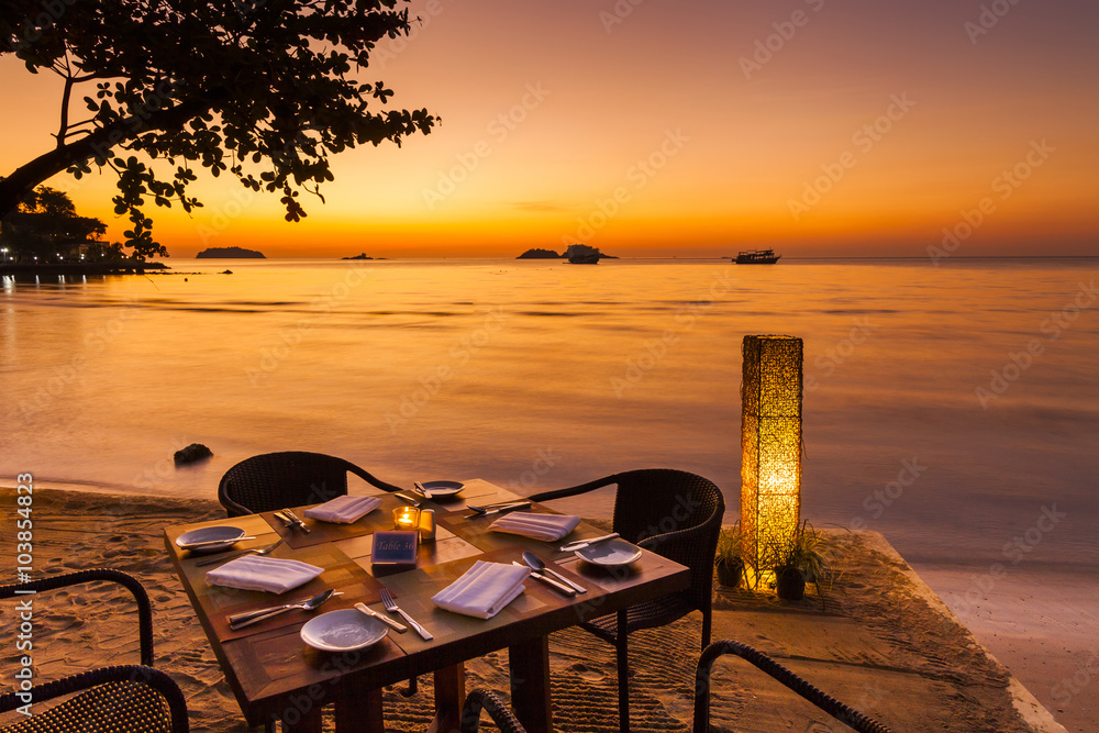 Naklejka premium Romantic sunset on the shore of a tropical island. Cafe on the b