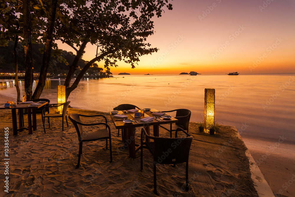 Naklejka premium Romantic sunset on the shore of a tropical island. Cafe on the b