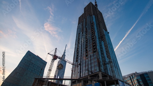 Sunset timelapse of skyscrapper construction works, pan