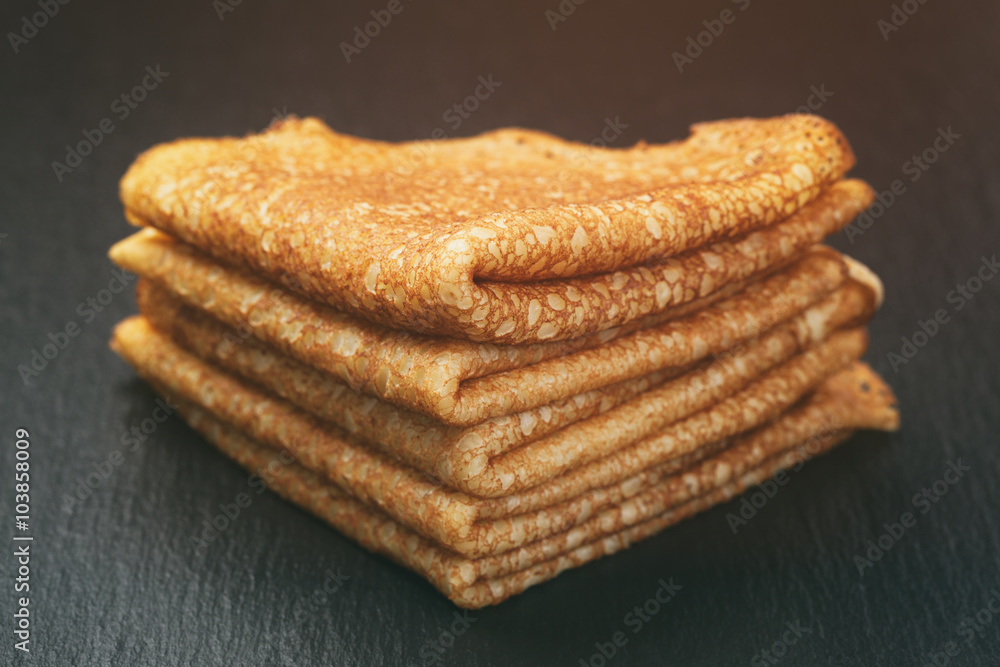 thin crepes or blinis folded in triangles on slate board, vintage toned thin crepes or blinis folded in triangles on slate board, vintage toned