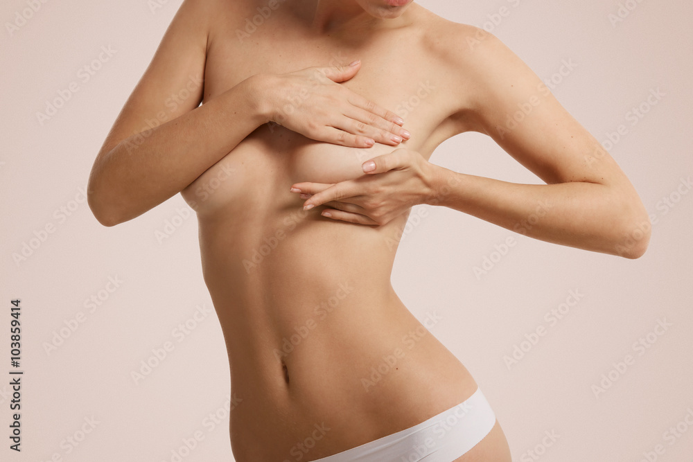 Fototapeta premium Breast cancer self check, healthy lifestyle concept. Young pretty woman examining her breast for lumps or signs of breast cancer