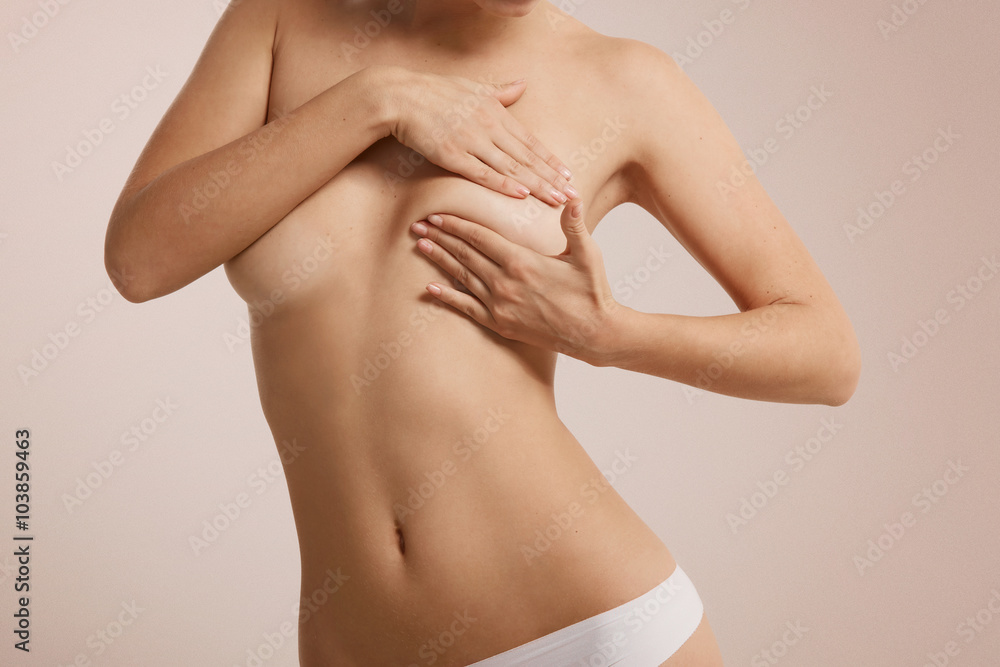 Young Caucasian adult woman examining her breast for lumps or signs of breast cancer Young Caucasian adult woman examining her breast for lumps or signs of breast cancer