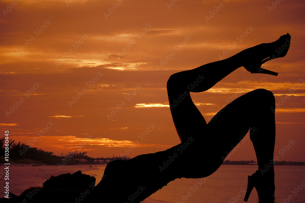 silhouette of woman by water in sunset lay on back leg up silhouette of woman by water in sunset lay on back leg up