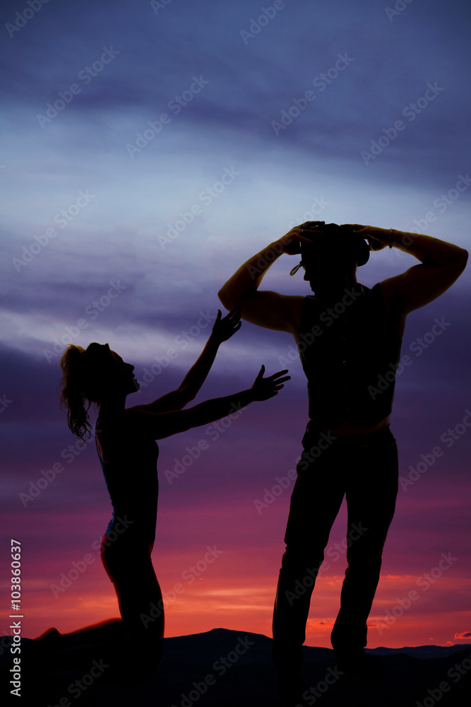 silhouette of woman on her knees in the sunset reaching up with