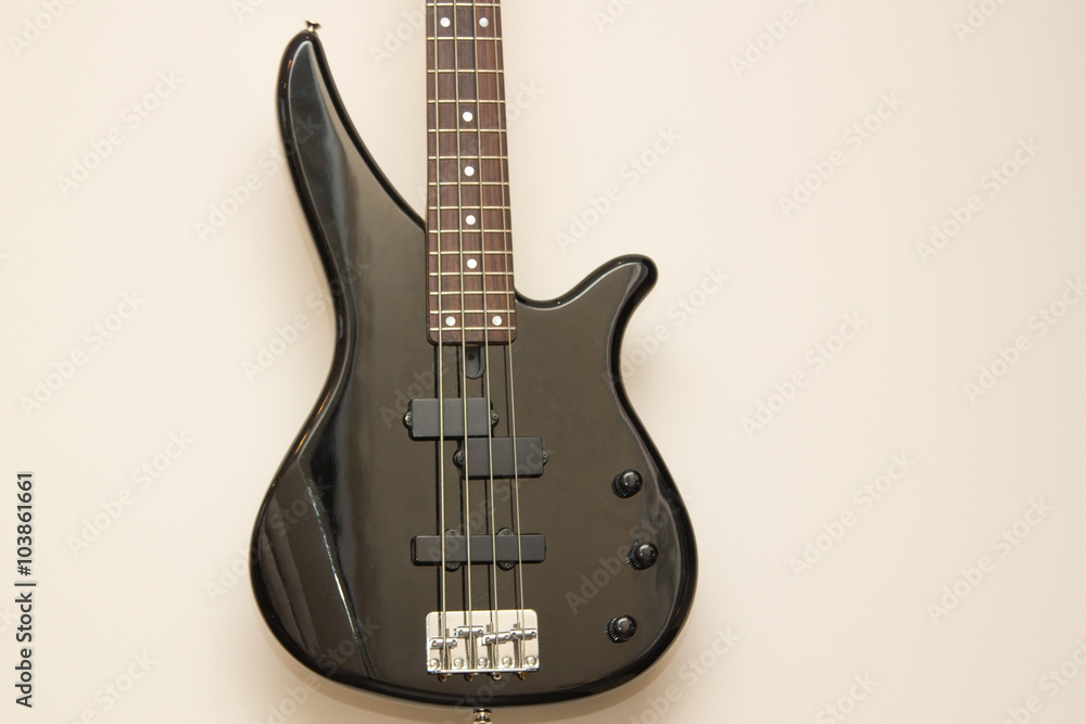 black bass electric guitar hanging on the wall