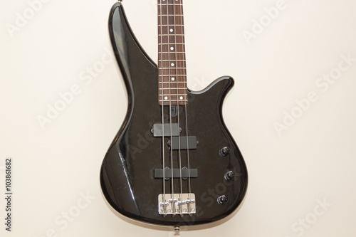 black bass electric guitar hanging on the wall