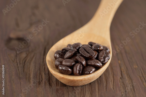 Coffee beans / Roasted coffee beans in wooden spoon on wooden floor.