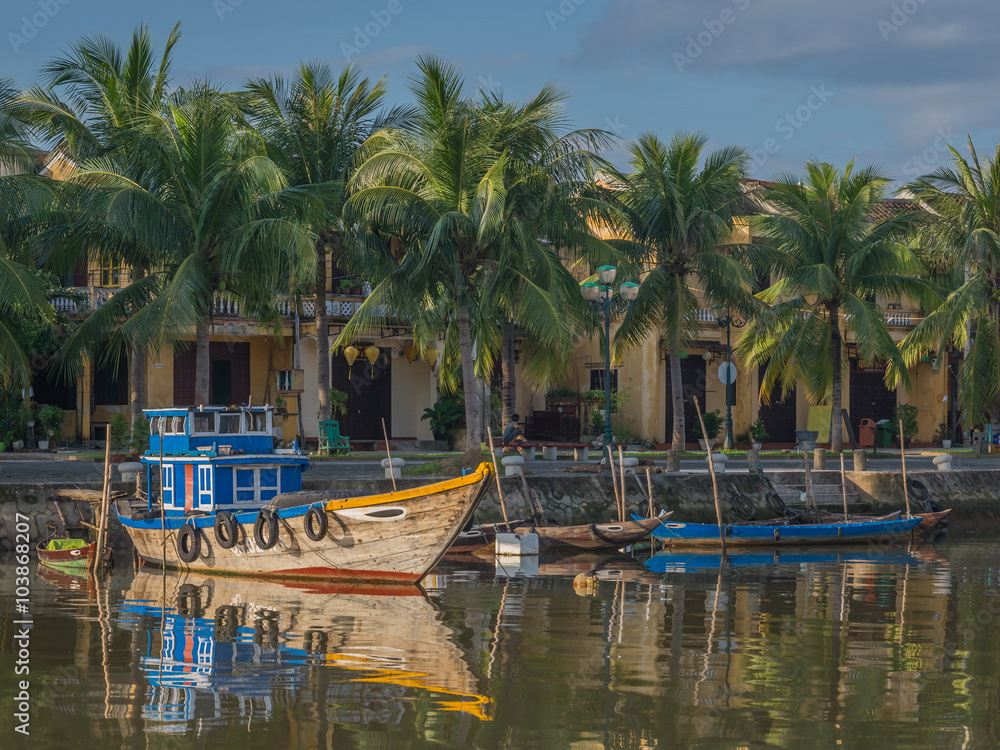 Obraz premium Morning sun on traditional wooden boats along the Thu Bon River in Hoi An, Vietnam.
