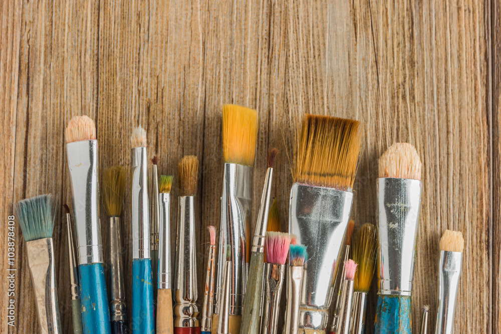 Artist paint brushes over rustic wooden texture