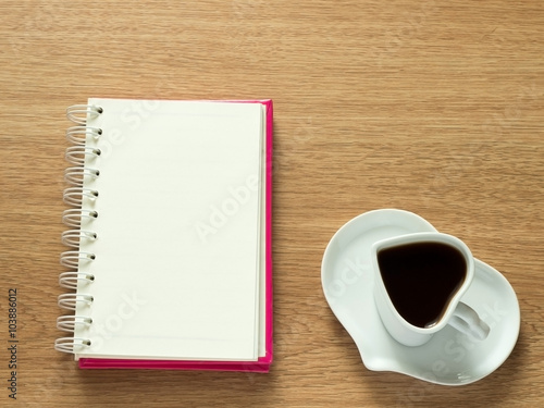 Heart shape of cup with coffee and heart shape of plate with opened book for diary. Love coffee. Top view. Happy Valentines Day background.